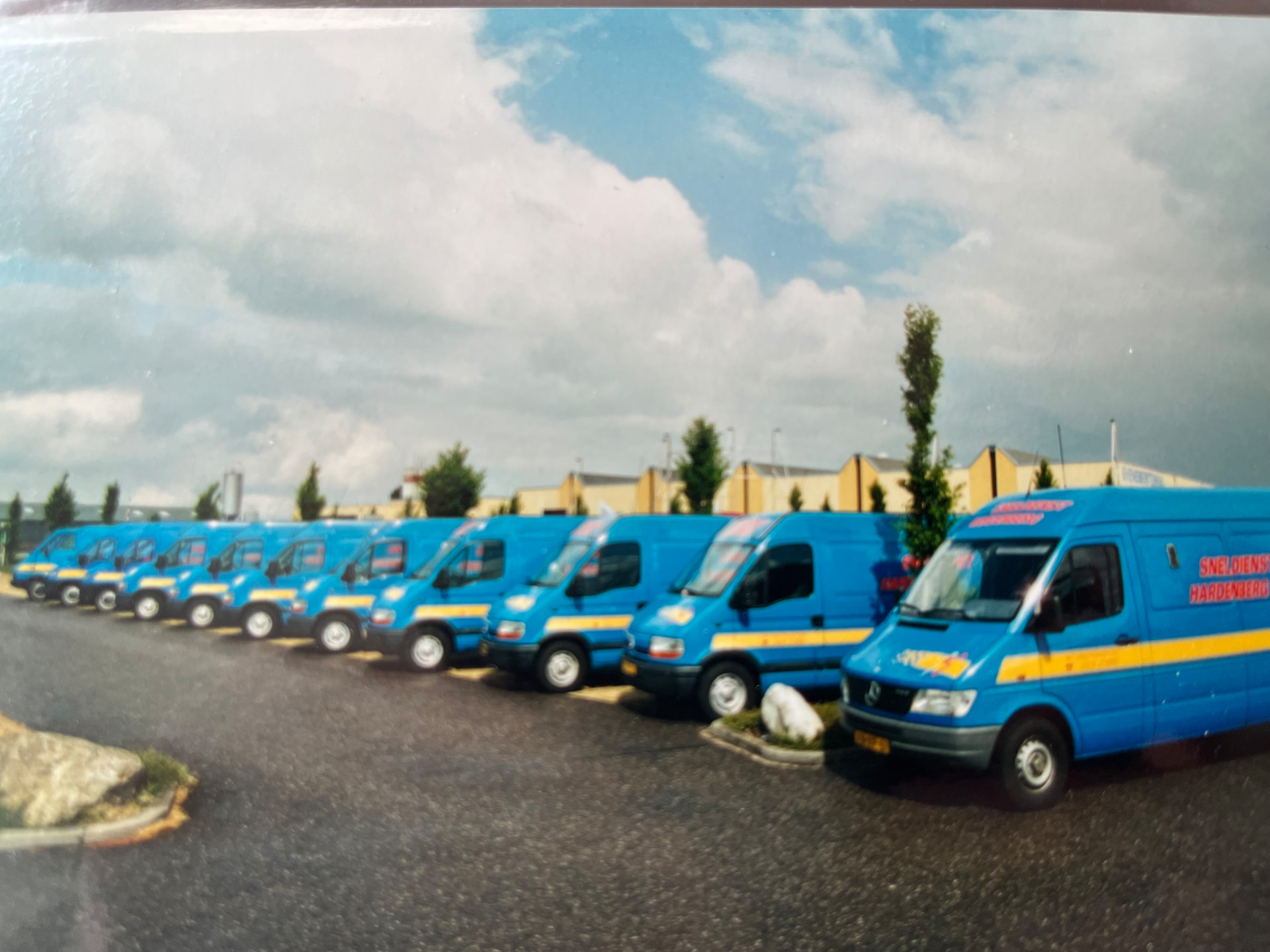 Rij blauwe Sneldienst-bestelbussen op het terrein