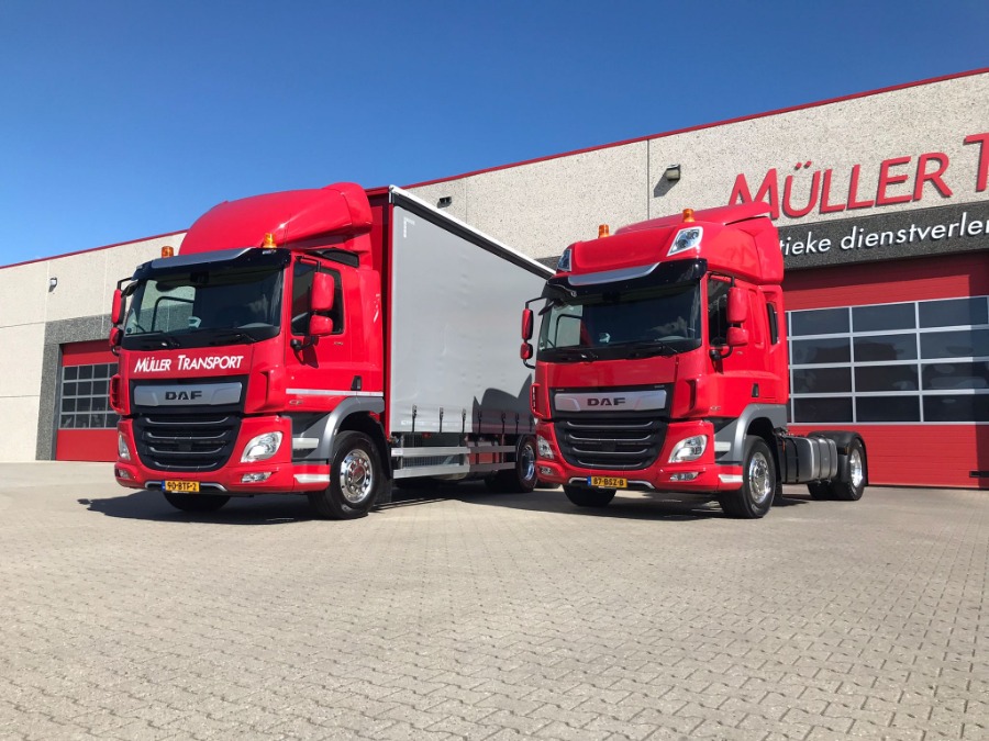 Twee rode vrachtwagens van Müller Transport voor het pand